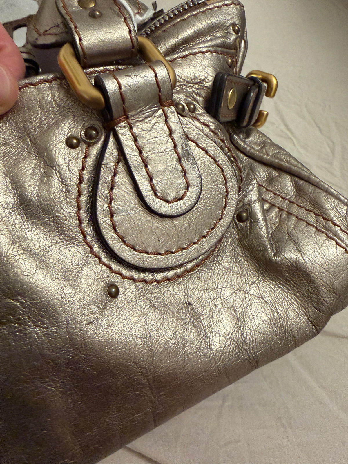 Chloé beige metallic handbag with oversized brass padlock and dual rolled handles.