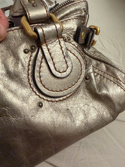 Chloé beige metallic handbag with oversized brass padlock and dual rolled handles.