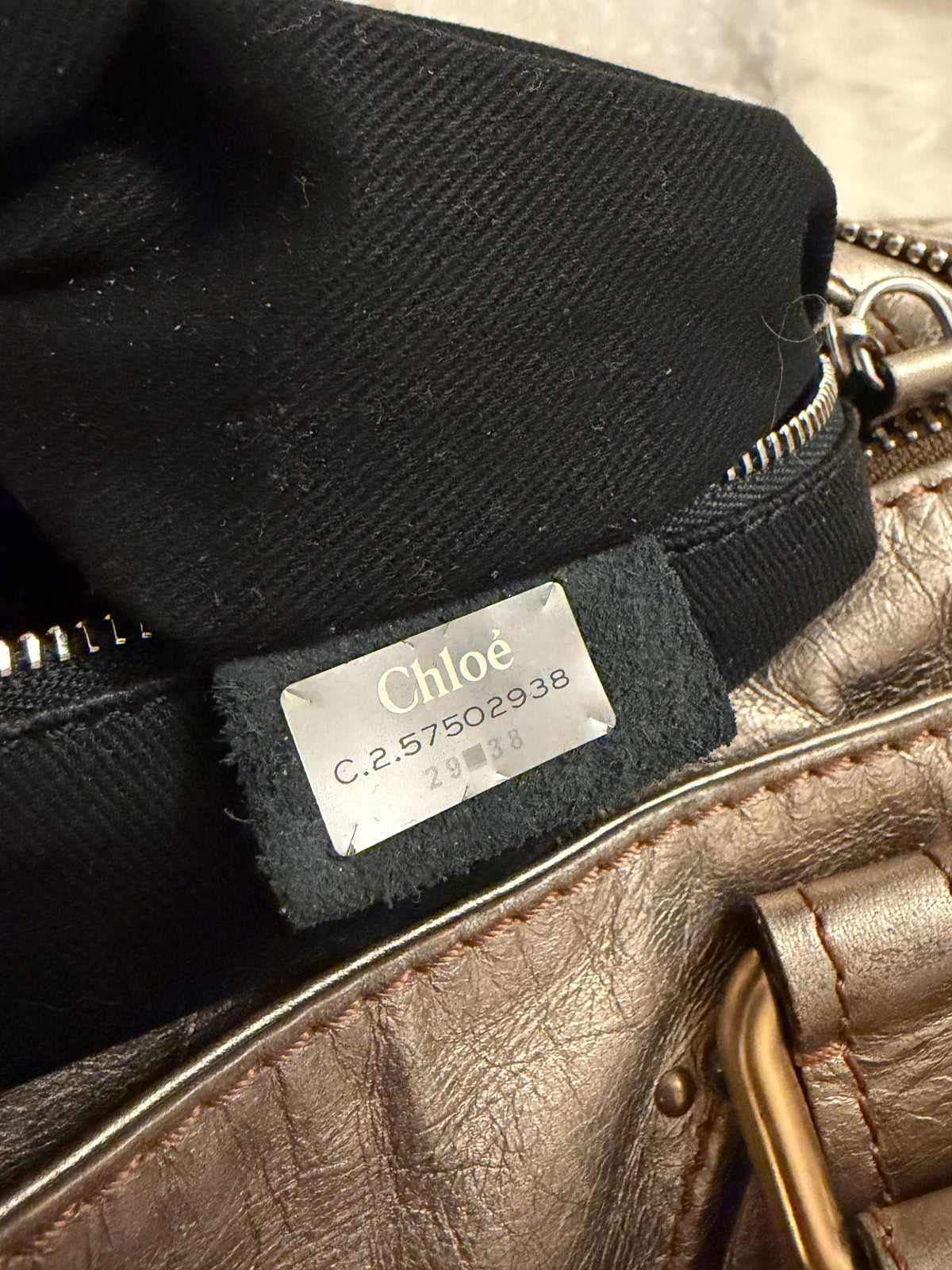 Chloé beige metallic handbag with oversized brass padlock and dual rolled handles.