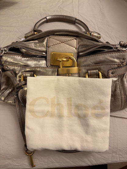 Chloé beige metallic handbag with oversized brass padlock and dual rolled handles.