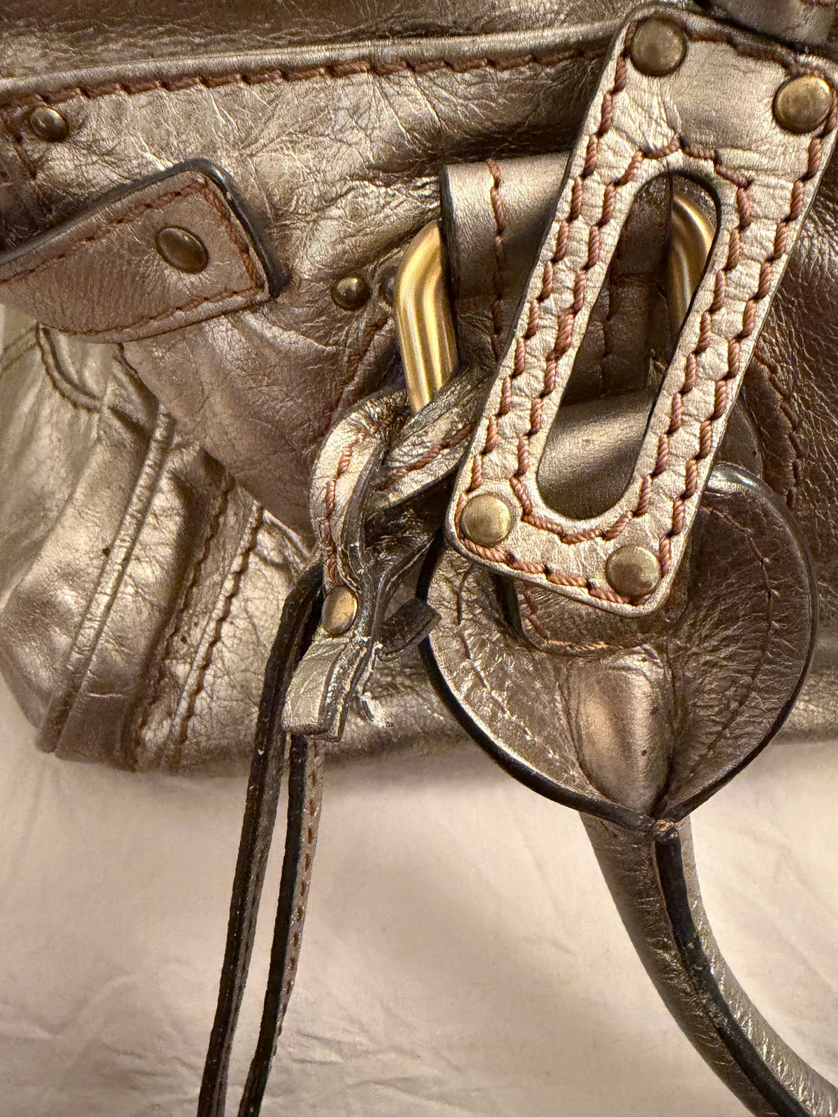Chloé beige metallic handbag with oversized brass padlock and dual rolled handles.
